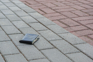 Black wallet on pavement outdoors, space for text. Lost and found
