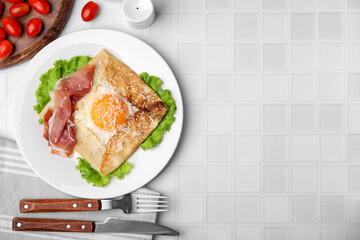 Delicious crepe with egg served on white tiled table, flat lay with space for text. Breton galette