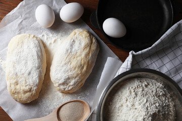Raw dough, eggs and flour on wooden table, flat lay. Cooking ciabatta