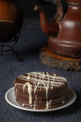Brown chocolate alfajor, typical candy in Argentina, with yerba mate and a kettle.