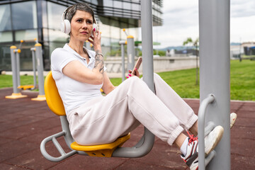 Mature caucasian woman training on leg press urban fitness machine