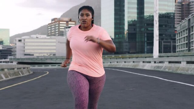 Runner, black woman and fitness with running in street, breathing and sweat with earphones for music. Plus size athlete with workout, weightloss and exercise, diet and health, training in city.