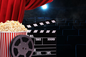 Tasty popcorn, film reel and clapperboard under red main curtain in cinema, space for text