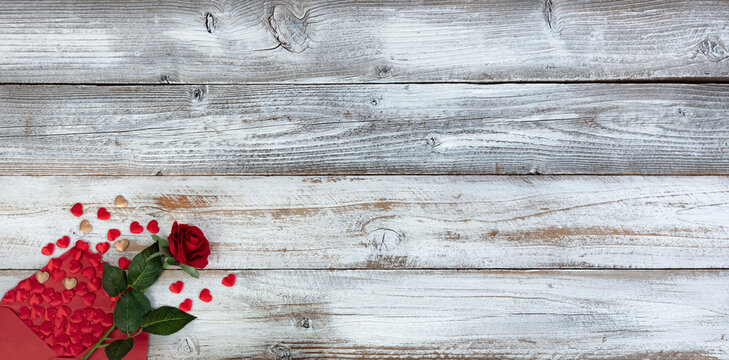 Love pouring out of envelope with rose flower and hearts on white rustic wood for a happy Valentines day