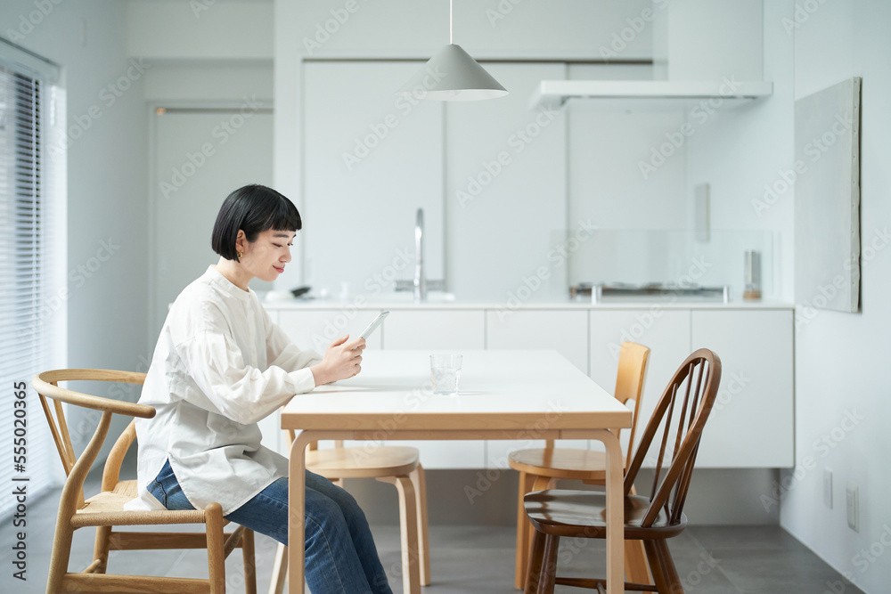 Wall mural 部屋でスマートフォンを操作する若い女性