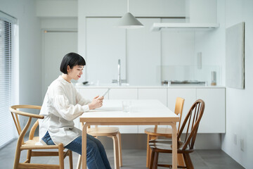 部屋でスマートフォンを操作する若い女性