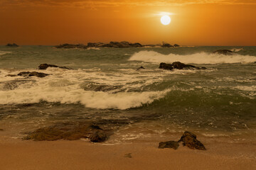 beautiful sunset over the ocean with rocks in the foreground