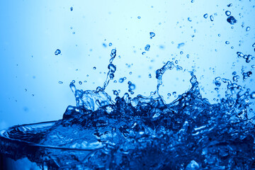 Fototapeta na wymiar Drops of water falling into deep blue water