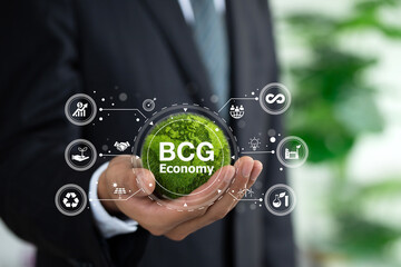 BCG concept for sustainable economy development. Bio economy, circle economy, green economy.Businessman holding the green world with BCG icons. New economic model for inclusive and sustainable growth.