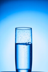 closeup of pouring water on the cup on transparent blue background