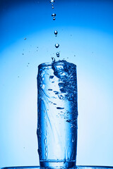 closeup of pouring water on the cup on transparent blue background