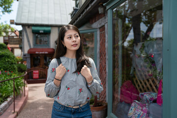 curious asian Korean girl tourist looking at charming stores with glass windows as she wanders on the street through Danish village in downtown solvang usa