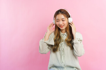 Young women wearing headphone to listening music with empty space on isolated pink background