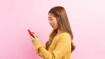 Young woman excited face while surfing social media on smartphone isolated on pink background