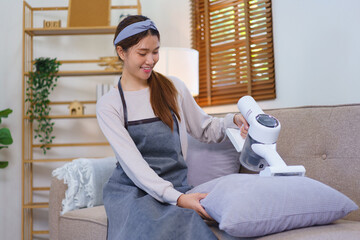 Housekeeping concept, Housemaid use vacuum cleaner to vacuuming and cleaning the couch and pillow
