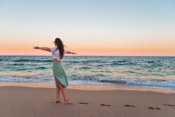 Happy woman enjoying beautiful sunset on the beach