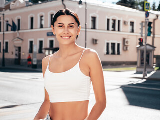 Young beautiful smiling hipster woman in trendy summer white top and shorts clothes. Sexy carefree model posing in the street at sunny day. Positive brunette female. Cheerful and happy