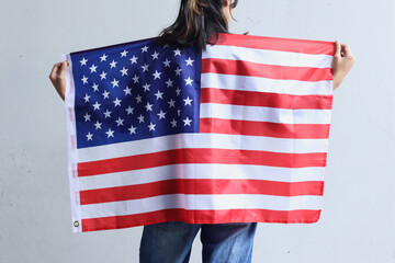 Young woman stands and holds an American flag.