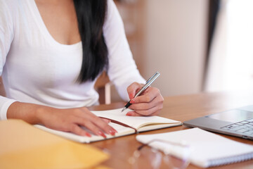 Close-up businesswoman sitting taking notes intensively and doing assigned tasks happily and purposefully.