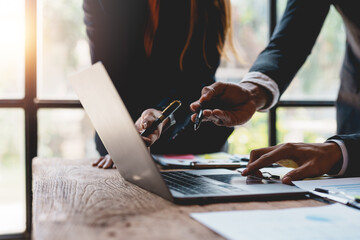 Fototapeta premium Businesspeople hand pointing at laptop computer to view business figures, graphs, charts, analyzing corporate finance marketing concepts Plan a marketing strategy on a laptop.