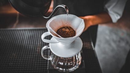 Hand Drip Coffee, Barista pouring hot water on roasted coffee ground with filter,and man is pouring hot coffee from the coffee pot into the white cup coffee on the table in the morning,vintage