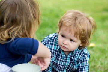 Portrait of cute little caucasian boy having fun in garden. Child on green grass lawn during walk in yard. Happy childhood and baby healthcare.