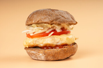 burger with vegetables and juicy bun on a beige background closeup