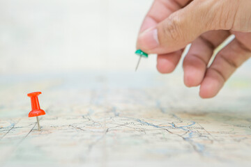 Selective focus of Red pin  and blurred hand holding a pin on map background