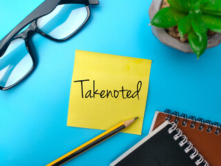 Sticky notes and pencil with the word Takenoted on blue background.