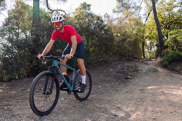 happy cyclist training in the forest with his mountain bike, concept of freedom and sport in nature, copy space for text