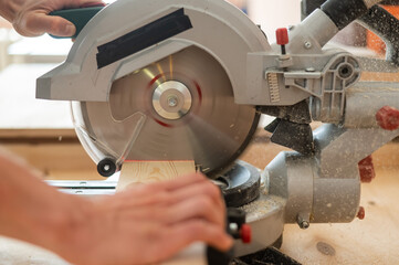 Master cuts the board with a circular saw in the workshop. 