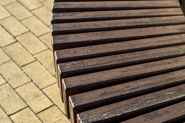 Close-up of part of the seat of a bench made of wooden bars assembled with a lattice. Unusual wooden construction.