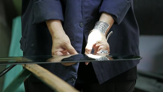 Process of preparing windshield for replacement in car service. A worker applies special adhesive sealant to the windscreen before installation on the auto.