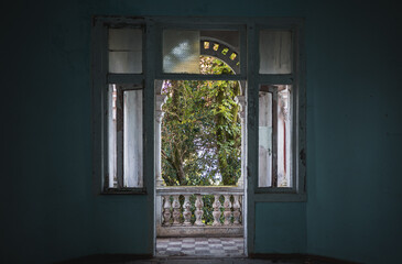 Fototapeta na wymiar View from abandoned building room through open balcony door.