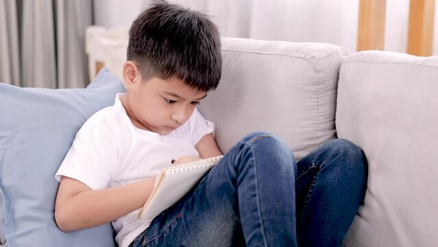 4K, Asian cute boy, sitting on sofa in living room at home, Painting picture drawn from his own imagination, he looked very determined, To accomplish it, to play with his father.