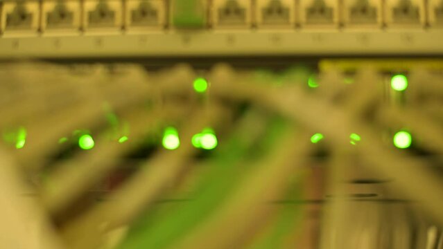 Verschwommene Sicht auf Blinkende bunte Lichter oder LED-Leuchten in einem Server Rack mit RJ45 und Lichtwellenkabel Anschl&uuml;sse an einem Netzwerkswitch in einem Rechenzentrum