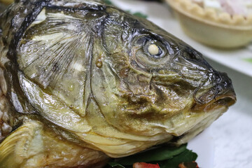 sea bream in salt after baking: detail of the head of the fish buried in salt showing the open mouth and teeth.