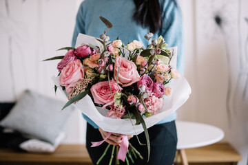 Very nice young woman holding big and beautiful bouquet of fresh ohara roses smaller roses, eucalyptus, eustoma in tender pink colors, cropped photo, bouquet close up - 555055525