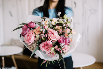 Very nice young woman holding big and beautiful bouquet of fresh ohara roses smaller roses, eucalyptus, eustoma in tender pink colors, cropped photo, bouquet close up - 555055529