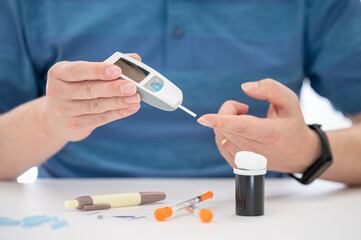 Man measures his blood sugar. Glaucometer, blood sample test, diabetes concept.