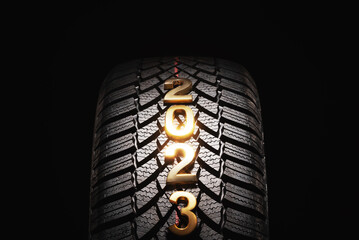 Happy new year 2023 and winter Car tire for snow isolated on black background. New automobile tyre for snowy road.