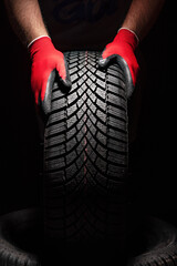 Car tire service and hands of mechanic holding new tyre on black background with copy space for text - 555057175