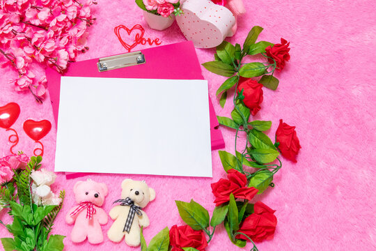 White blank A4 paper above a pink clipboard surrounded by valentine themed decorations
