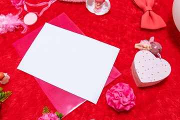 White blank A4 paper on the top of a pink envelope with fluffy red carped on the background