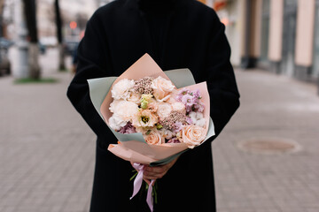Very nice young woman holding big and beautiful bouquet of fresh roses, eustoma, carnations flowers in pastel colors, cropped photo, bouquet close up - 555058789