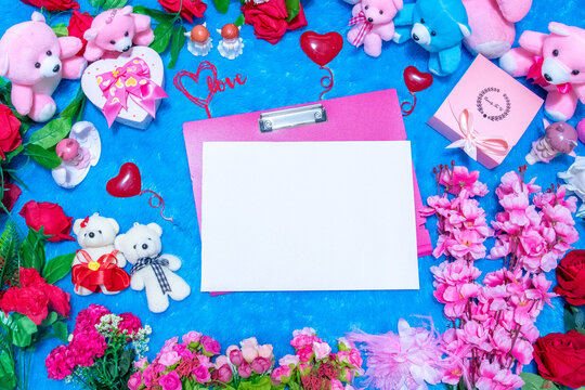 Blank white A4 paper on the top of a pink clipboard surrounded by valentine themed decorations