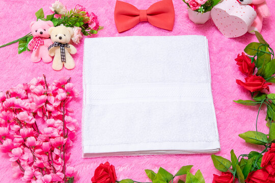 White blank towel above a fluffy pink carpet surrounded by valentine themed decorations