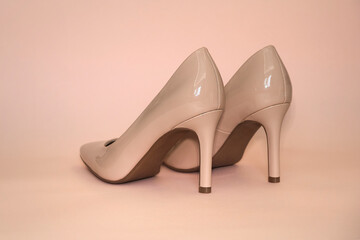 Closeup surface view of high heeled beige shoes on a beige background.