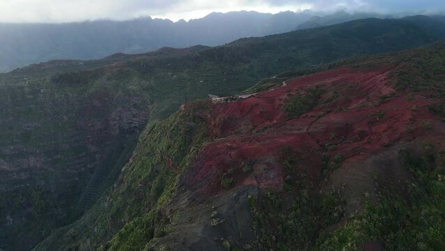 Aerial view of stunning viewpoint Mirador de Abrante with glass observation balcony above Agulo village in La Gomera island at sunrise. Restaurant on red clay.