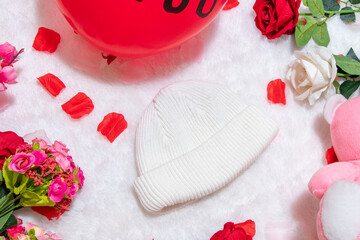 White blank beanie above a fluffy white carpet surrounded by valentine themed decorations